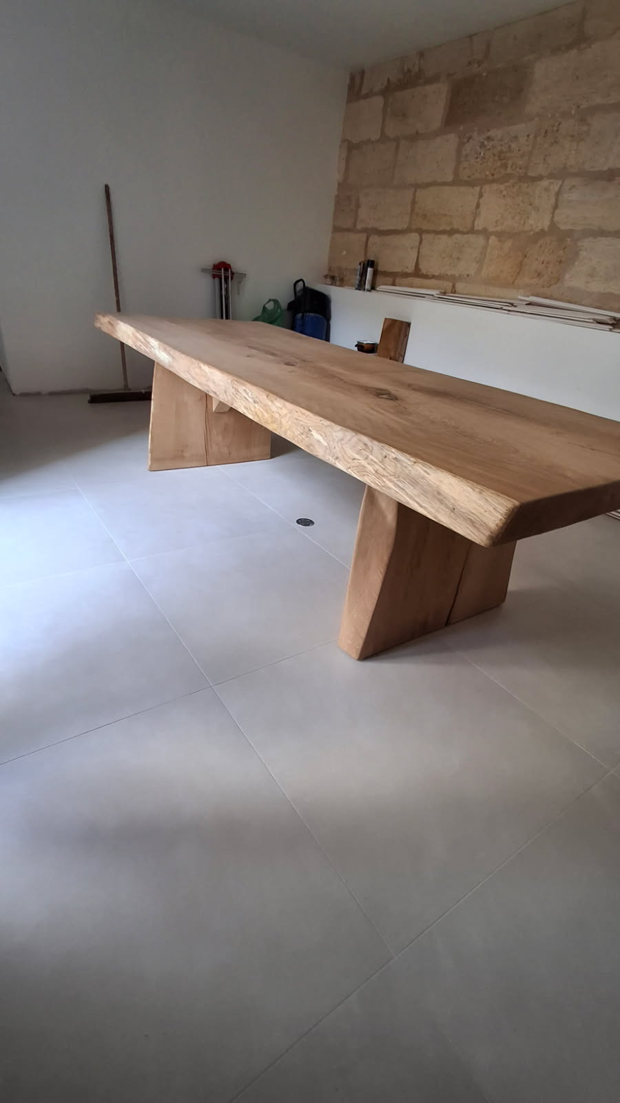 Table en bois massif sur mesure devant un mur en pierre